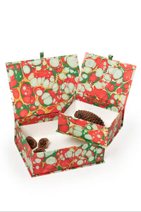 Hand-marbled keepsake box set in Christmas gems pattern with red, green, and white swirls, featuring open boxes with pinecones and small decorative items inside.