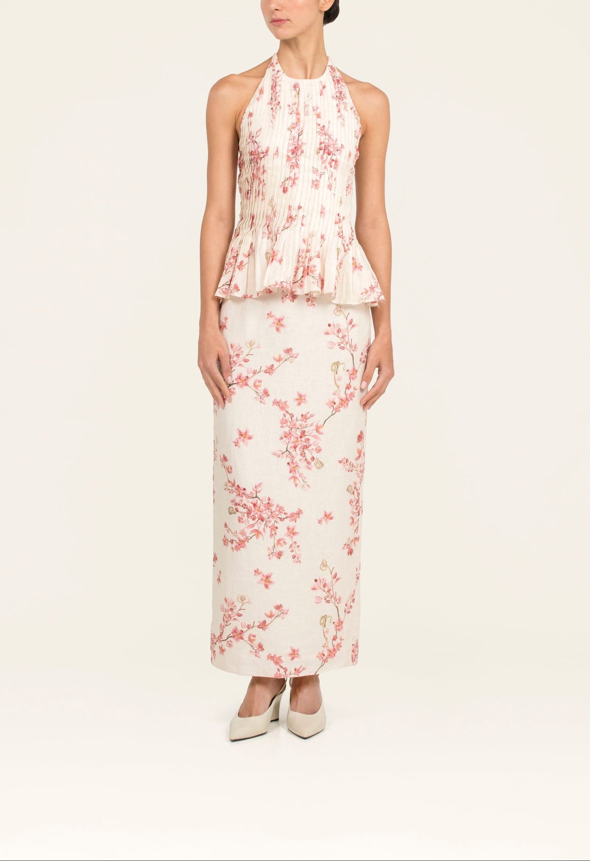 Front of Cana Cauca Top on model showing halter neckline, pleated bodice and peplum waist in cream floral linen
