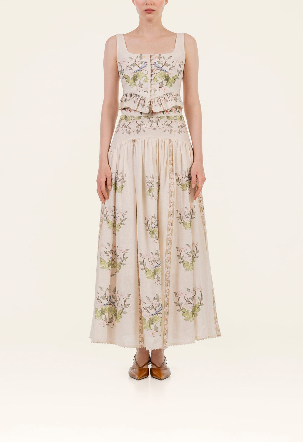 Front view of Curua Anhelo Skirt showing high-waist linen fit, hand-embroidered floral print and high-low hem on cream background