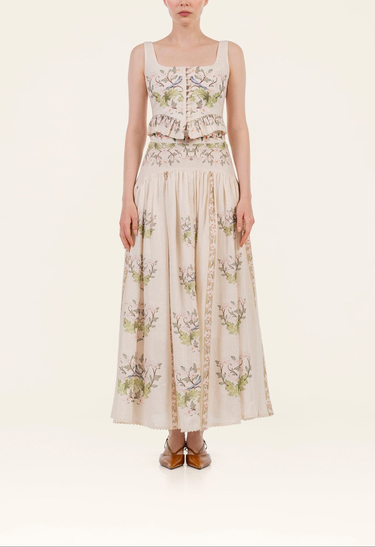 Front view of Curua Anhelo Skirt showing high-waist linen fit, hand-embroidered floral print and high-low hem on cream background