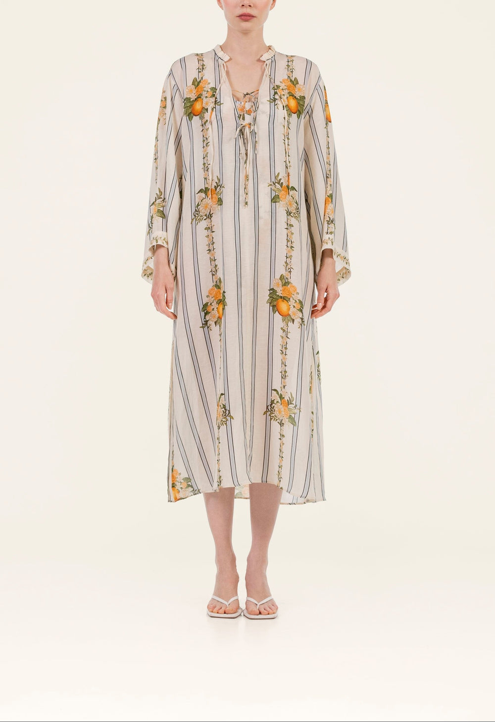 Front of Datil Valle Kaftan showing vertical stripes and orange floral print, tie neckline, long sleeves on light background