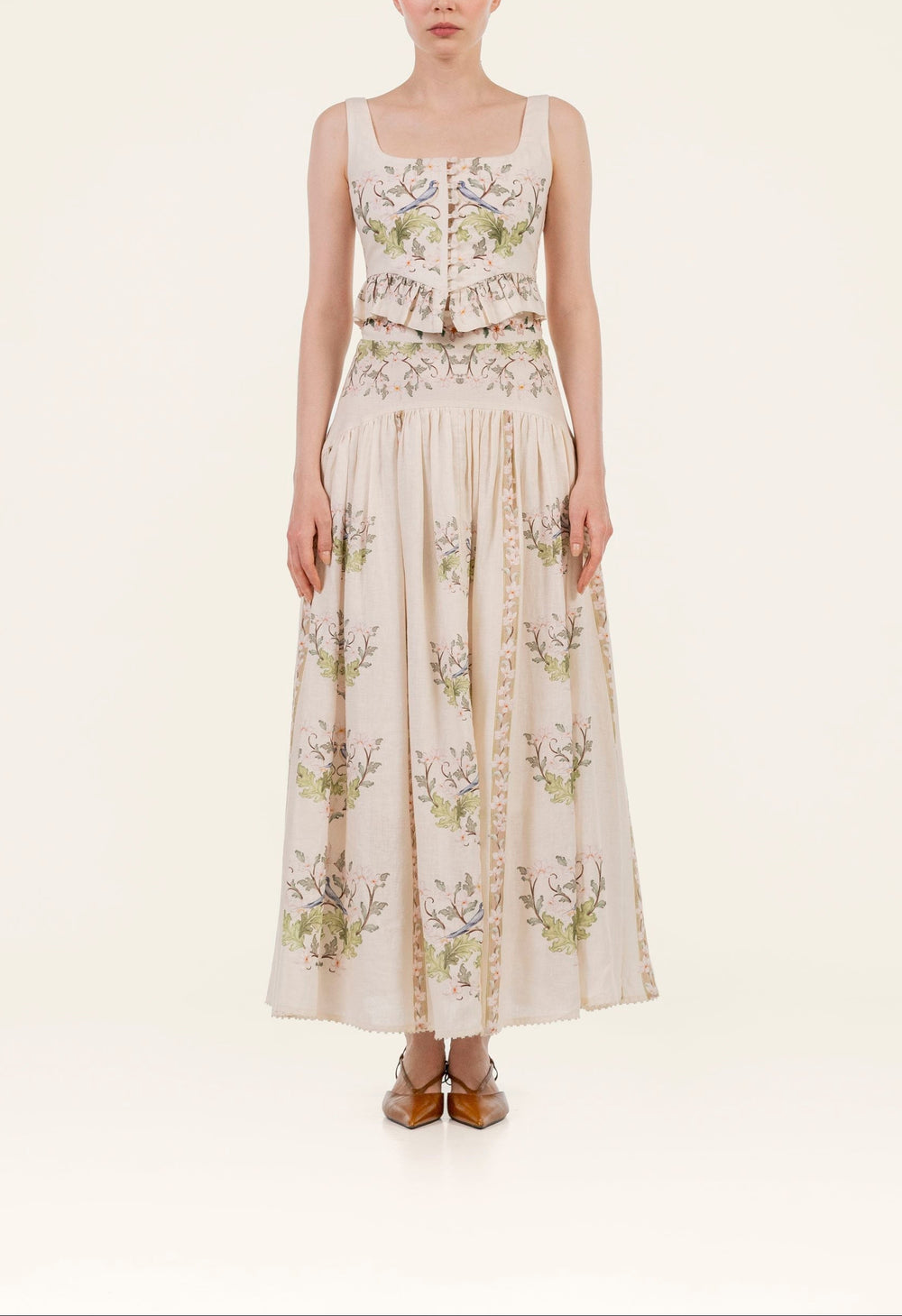 Front view of Eslabon Anhelo Top showcasing square neckline, ruffled peplum and embroidered floral linen on cream background