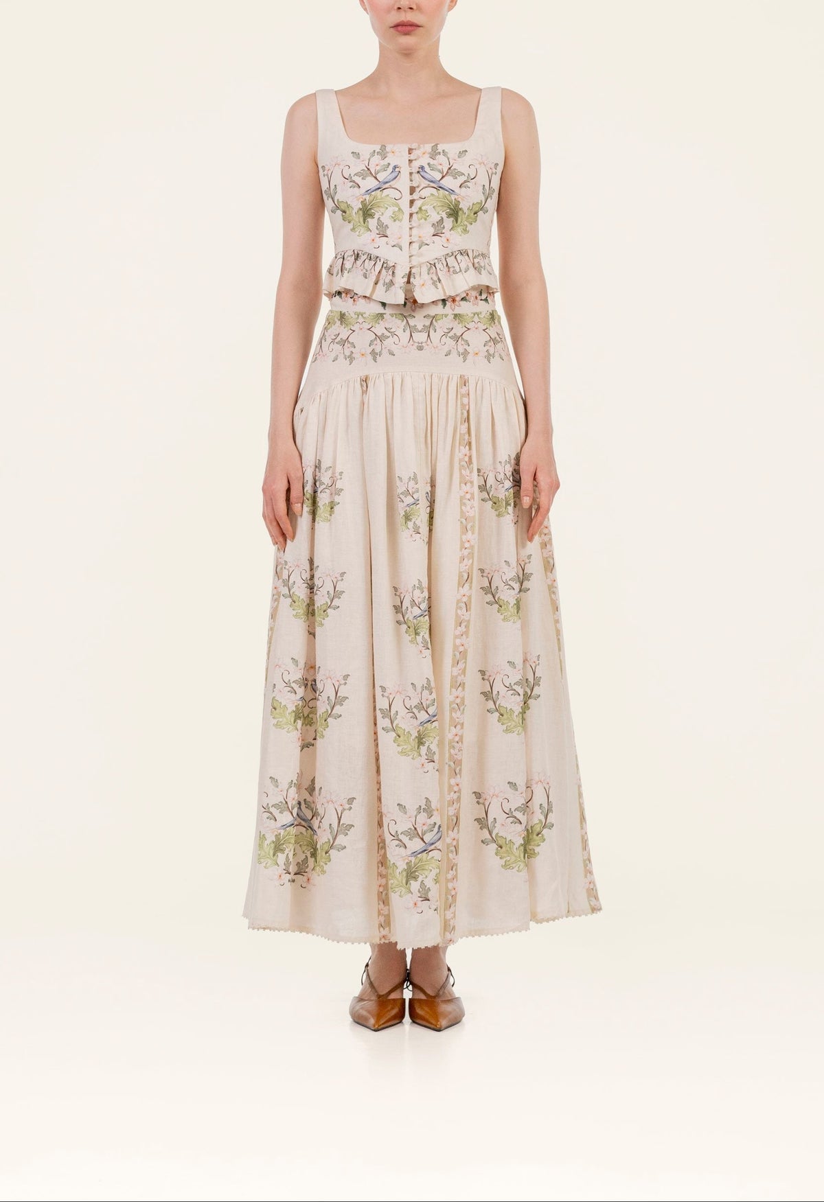 Front view of Eslabon Anhelo Top showcasing square neckline, ruffled peplum and embroidered floral linen on cream background