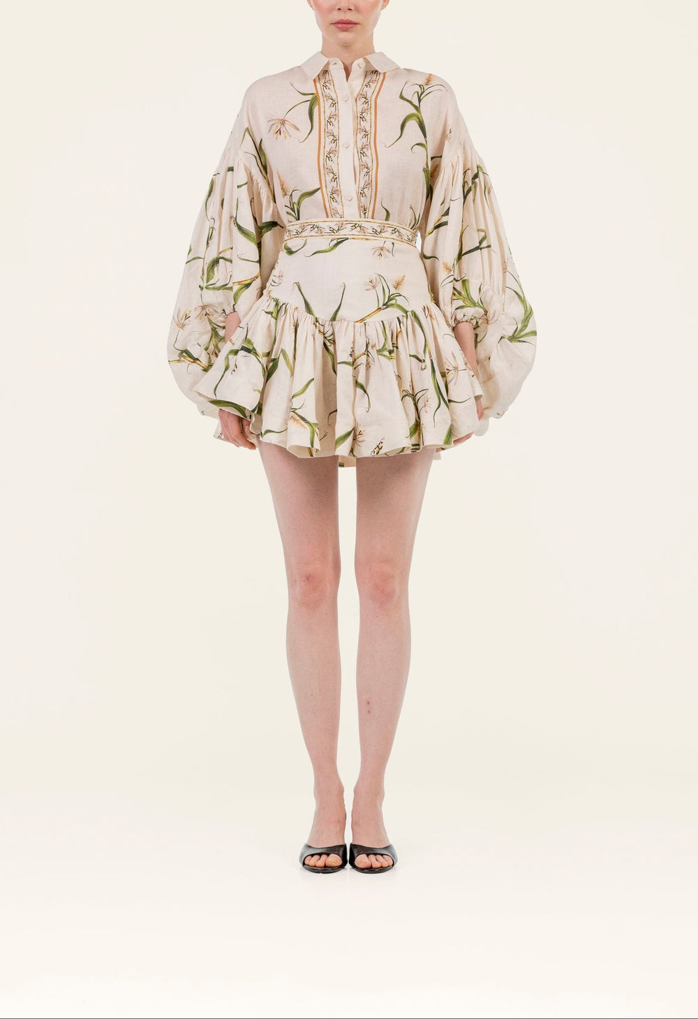 Front view of Jacarina Azucar Skirt on model showing fitted waistband and gathered mini skirt in cream floral linen on light background