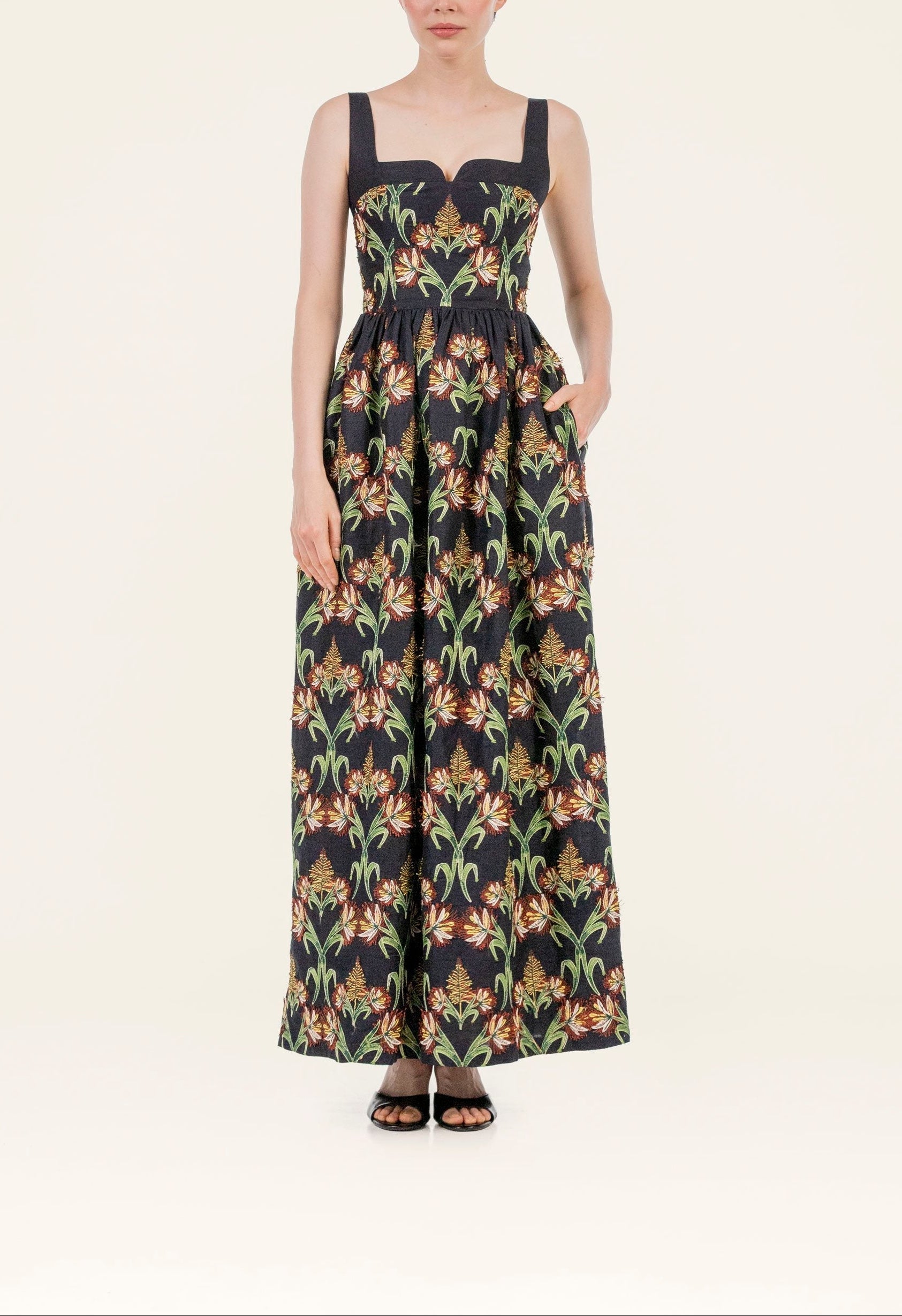 Front view of Jaspe Azucar Maxi Dress on model showing square neckline, fitted bodice, embroidered floral skirt and side pockets