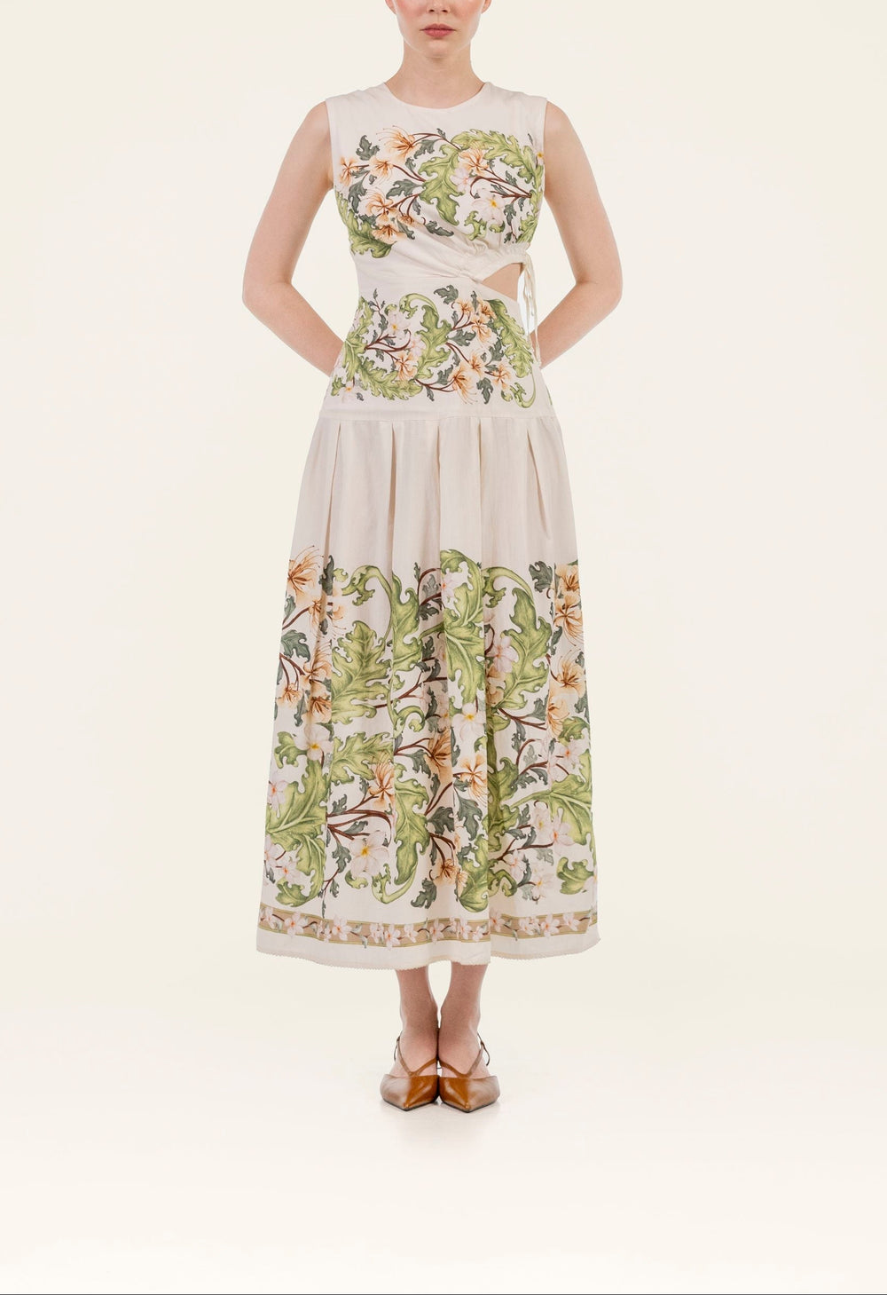 Front view of Otono Anhelo midi dress showing sleeveless bodice, side cutout tie, pleated skirt and green floral print on cream background