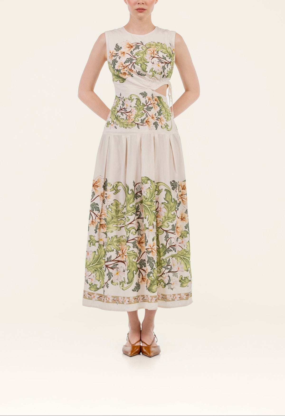 Front view of Otono Anhelo midi dress showing sleeveless bodice, side cutout tie, pleated skirt and green floral print on cream background