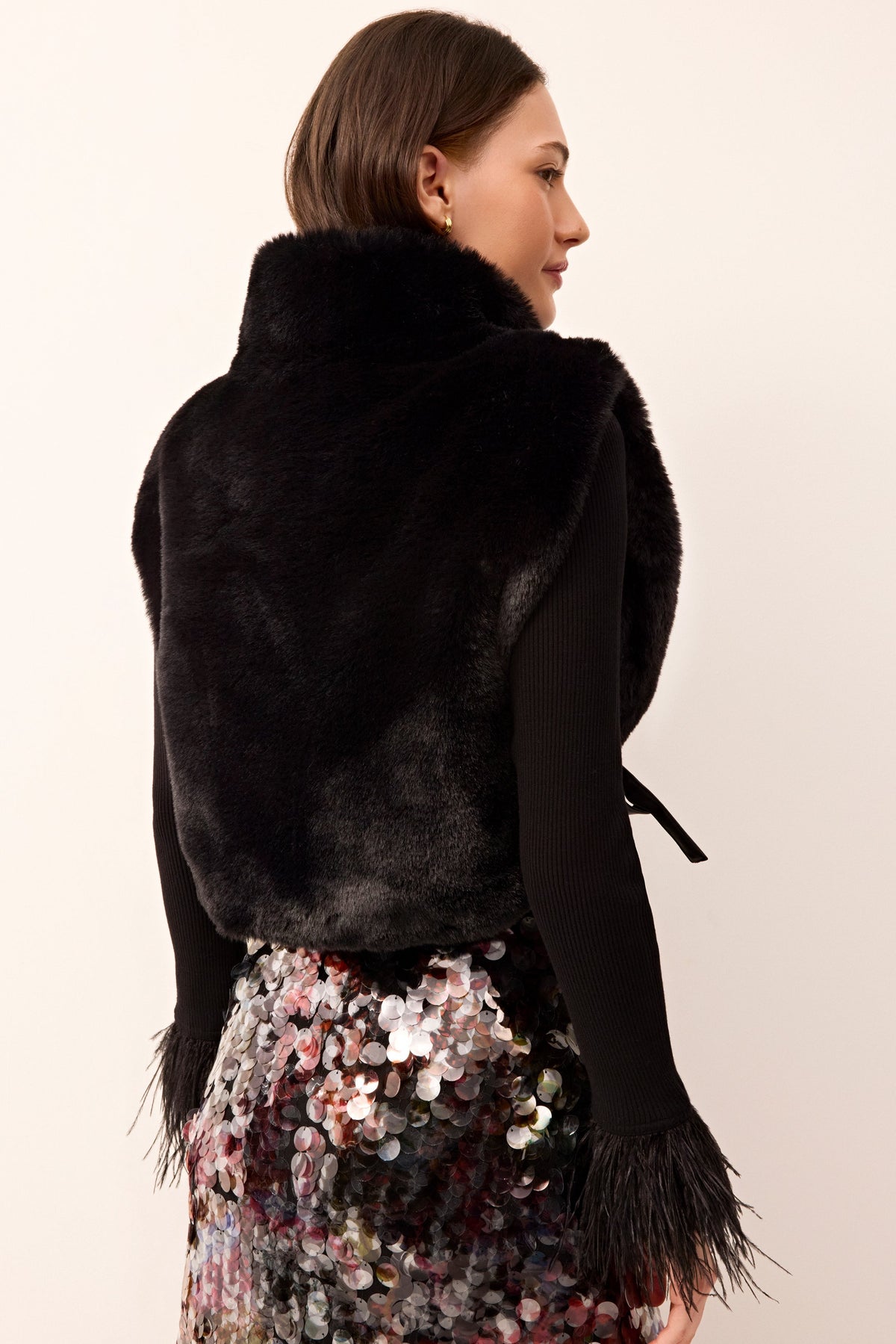 Sleeveless black furry vest featuring a turtleneck and adjustable tie sides