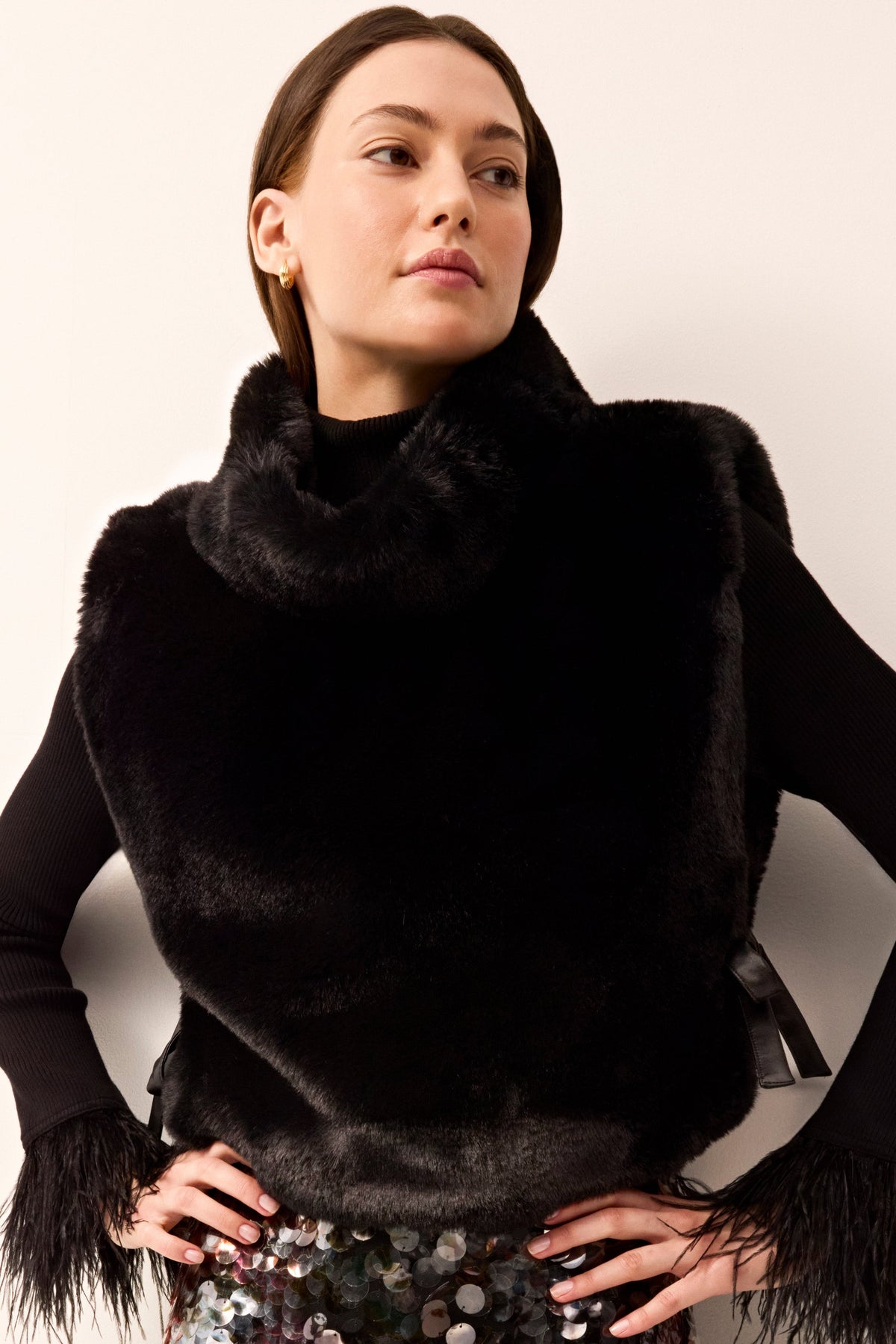 Black sleeveless vest in furry texture with a turtleneck and tie details at the sides.
