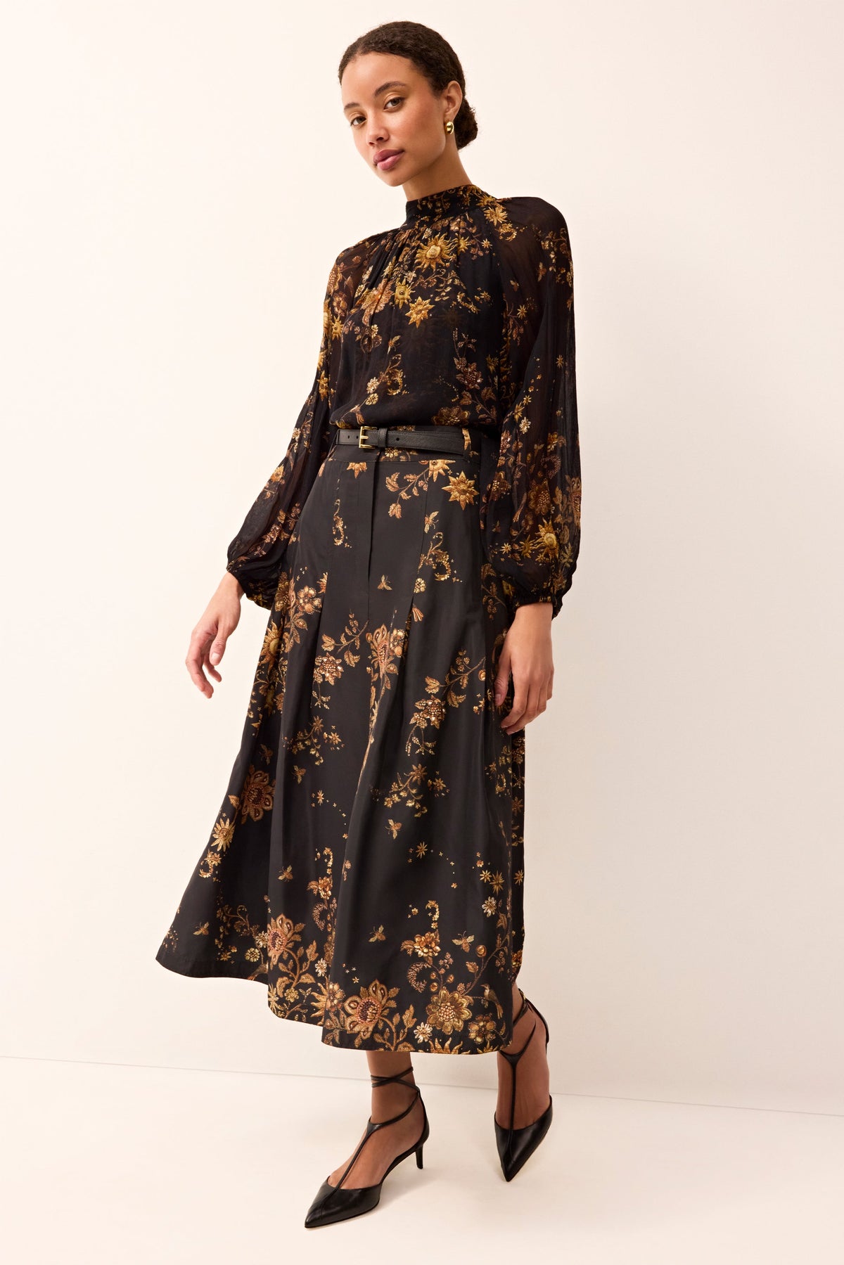 Fitted-waist midi skirt with a structured silhouette and elegant black-and-gold pattern.