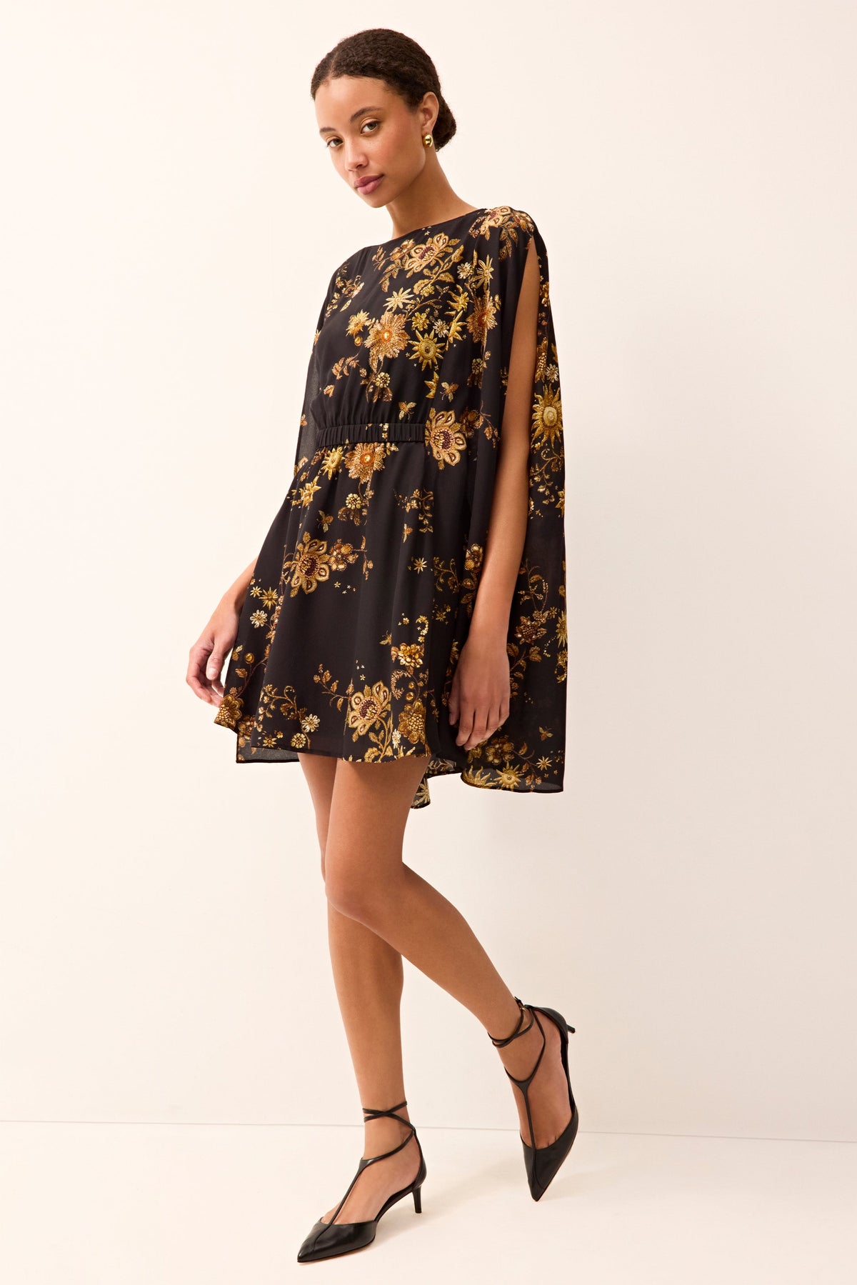 short dress with long cape sleeves with a cinched in waist and all over black and gold floral print