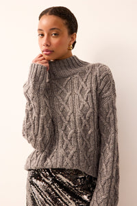 Long-sleeve silver sweater featuring a classic cable knit and shimmering silver metallic accents.