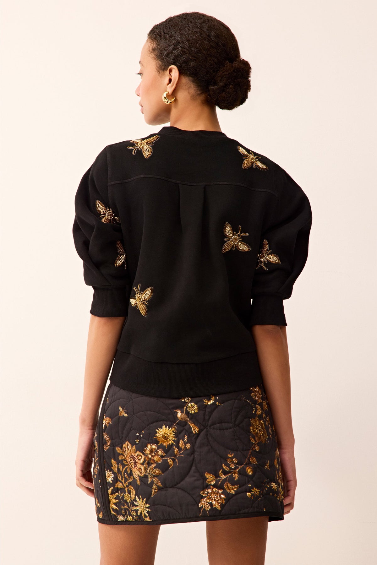 Black puff-sleeve sweater featuring allover beaded bee embroidery.