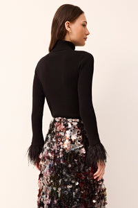 Form-fitting black turtleneck knit with long sleeves, detailed with feathered hems.
