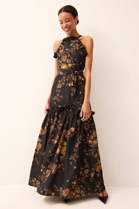 Flowing black formal gown with a halter neckline, ruffled skirt, and intricate gold floral print all over.