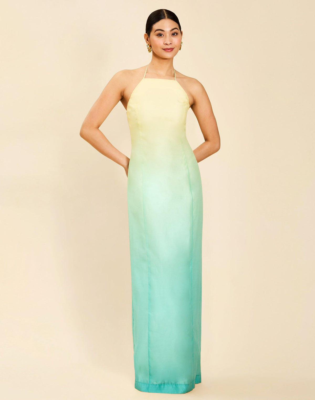 Woman wearing the Mestiza Mariposa Convertible Gown in Tuscan Sunrise print, featuring a column silhouette, removable cape overlay, racerback neckline, open back, self-tie halter straps, and linen organza fabrication.