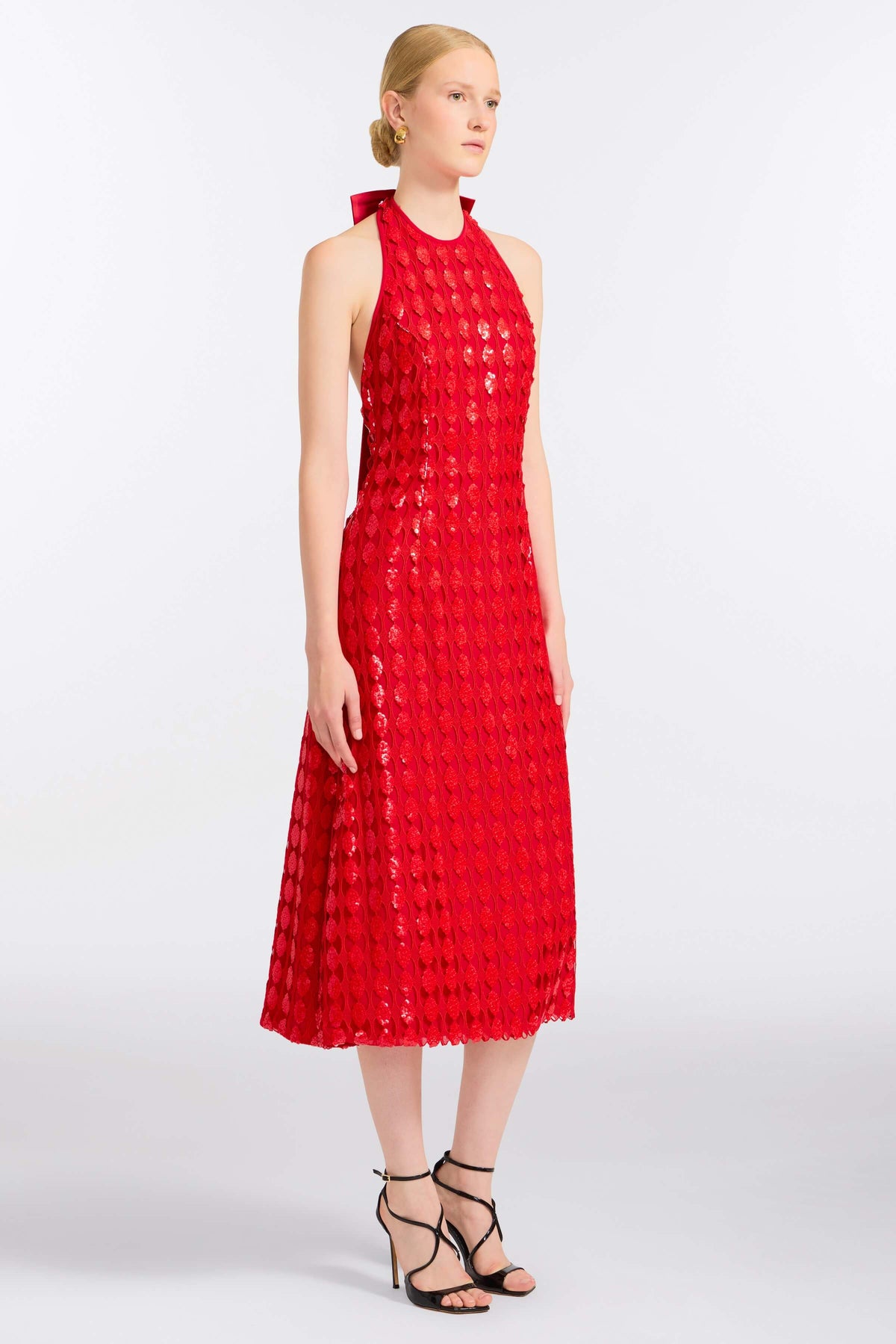 Three-quarter view of Ravenna Scarlet Halter Dress showcasing its fitted scarlet silhouette on a model against a light studio background