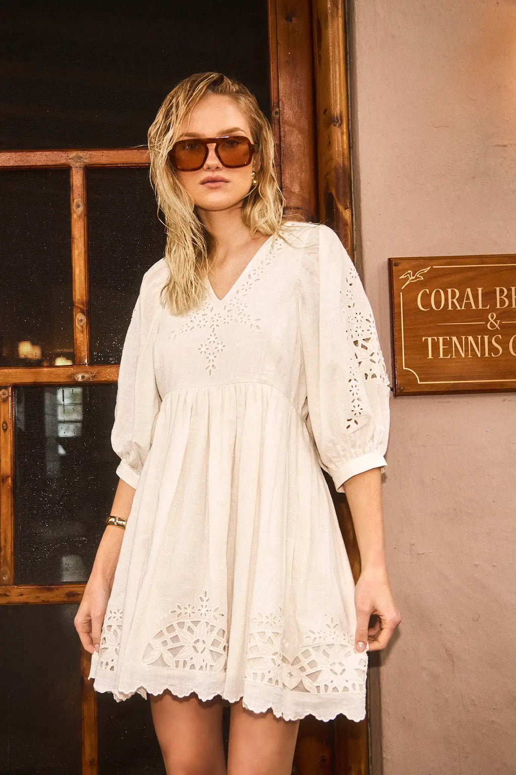 The Maya Dress in white, paired with brown sunglasses.