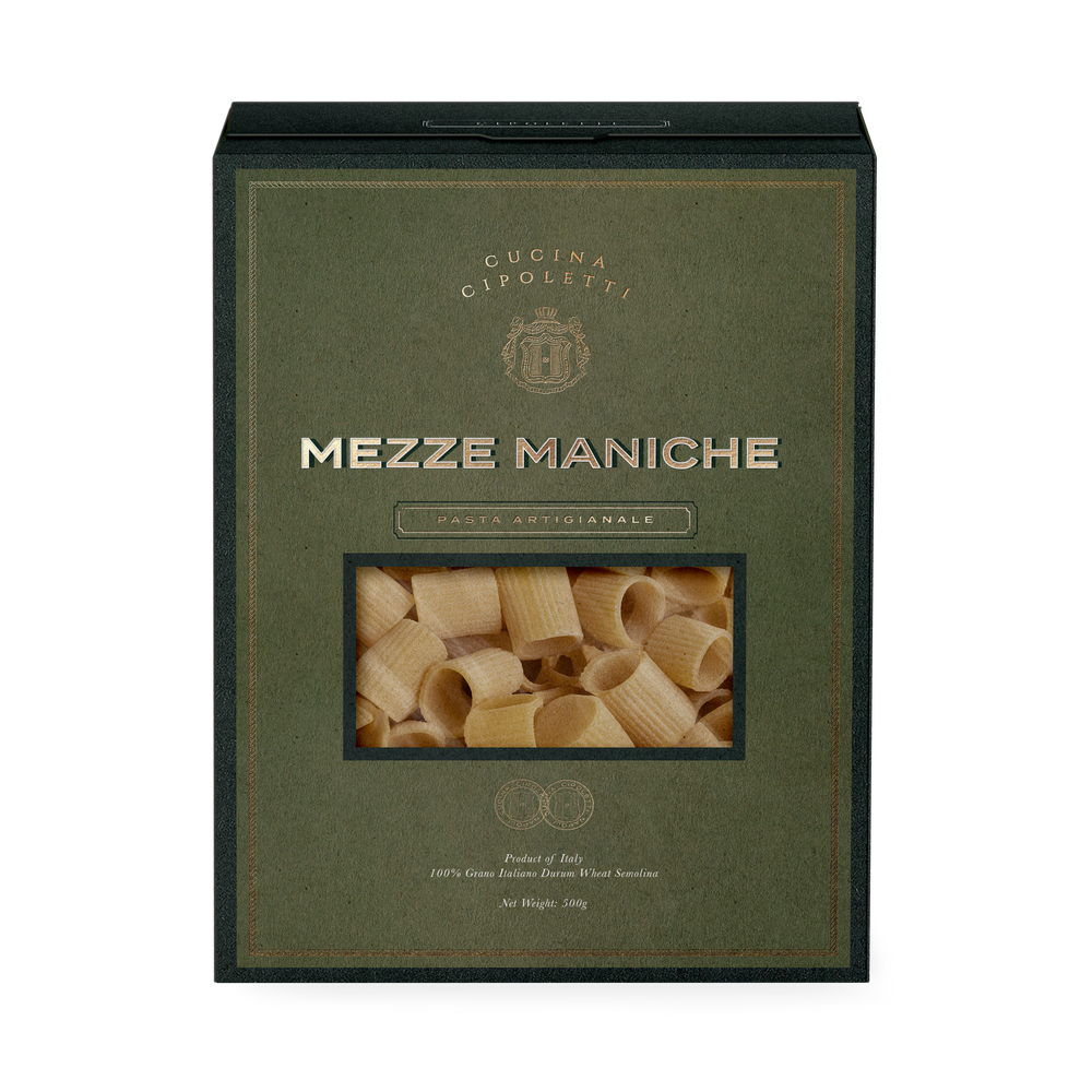 Front view of Mezze Maniche pasta box showcasing window of ridged short tube pasta on olive green textured background