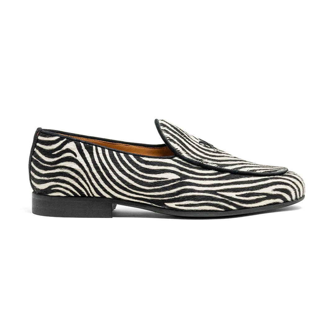 Side view of Women’s Zebra Print Milano Loafer showcasing black-and-white zebra print upper and low rubber sole with white background