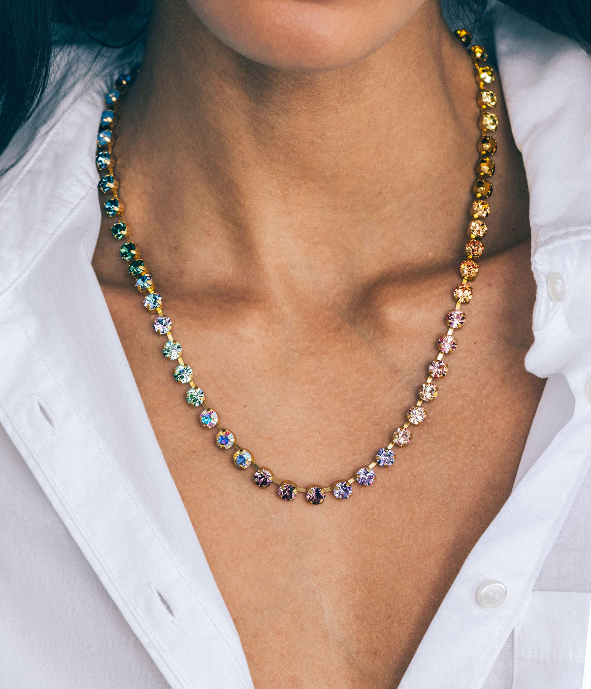 Close-up of Milly Slider Necklace in Daydreamer Ombré with hand-set pastel ombré crystals on gold chain on a white shirt