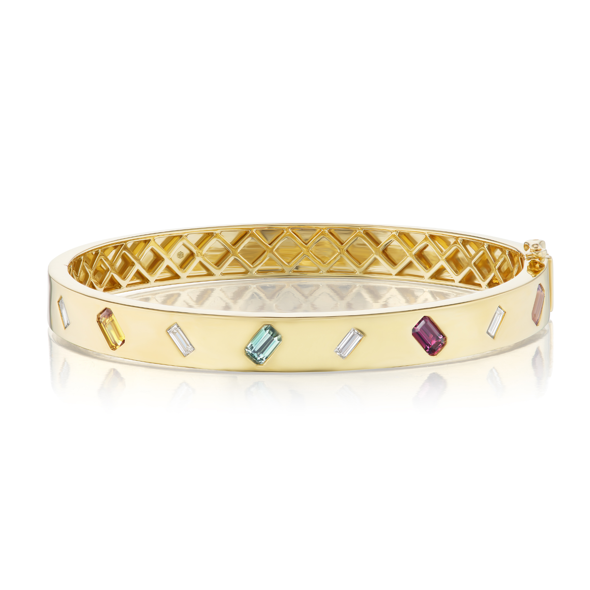 The Baguette Diamond and Dark Multicolor Emerald Cut Sapphire Bangle features an open lattice interior and geometric design with baguette diamonds and multicolored emerald cut sapphires around the edge.