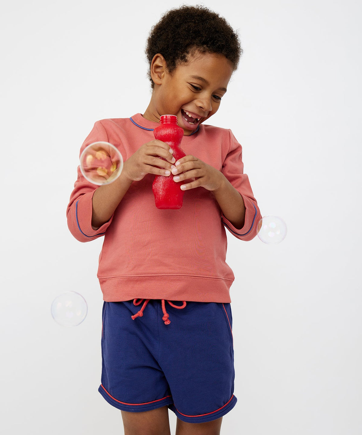 Front view of Bailey Short in Navy showcasing red contrast piping and half drawstring waist on a child against a white background