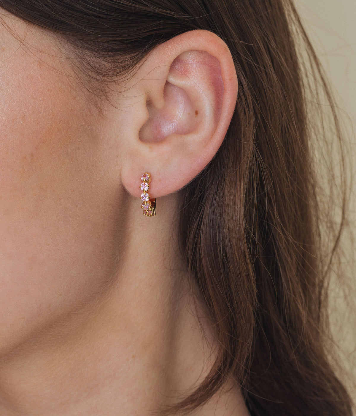 Close-up side view of Moira Hoops showcasing sparkling CZ stones and gold finish on a model’s ear