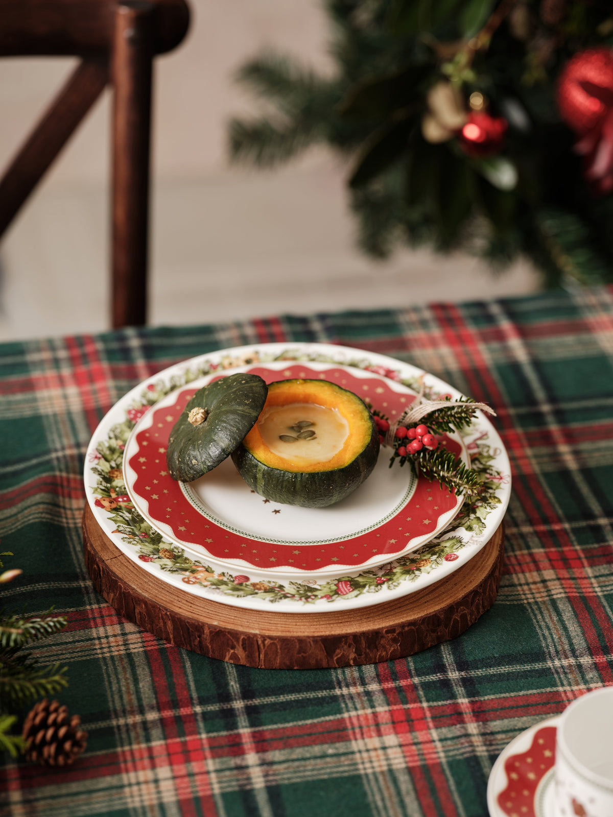My Noel salad plate on a plaid tablecloth holding a halved green squash filled with soup and garnished with an evergreen sprig