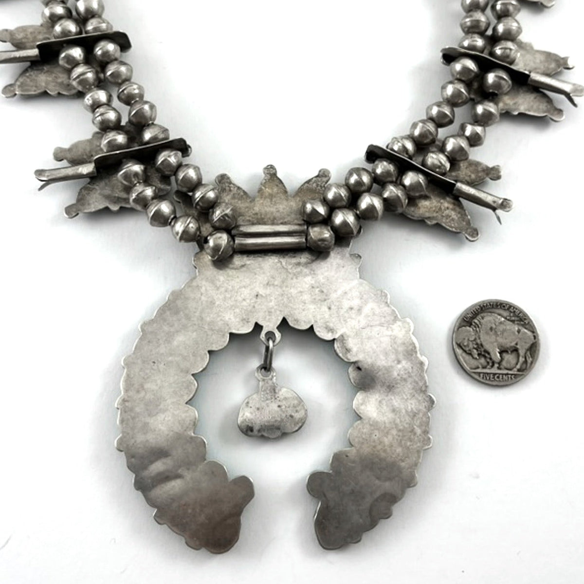 Close-up of vintage turquoise cluster necklace showcasing its large naja pendant and handmade sterling silver beads on a white background