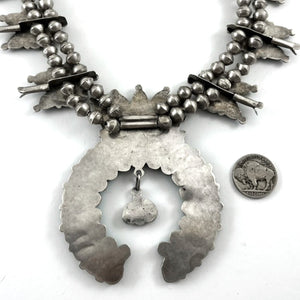 Close-up of vintage turquoise cluster necklace showcasing its large naja pendant and handmade sterling silver beads on a white background