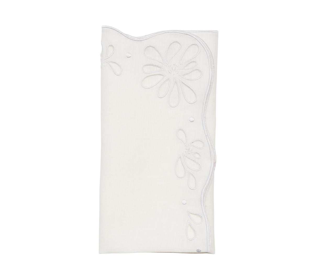 Folded Bloom napkin showing hand-cut eyelet floral embroidery on white linen against a white background