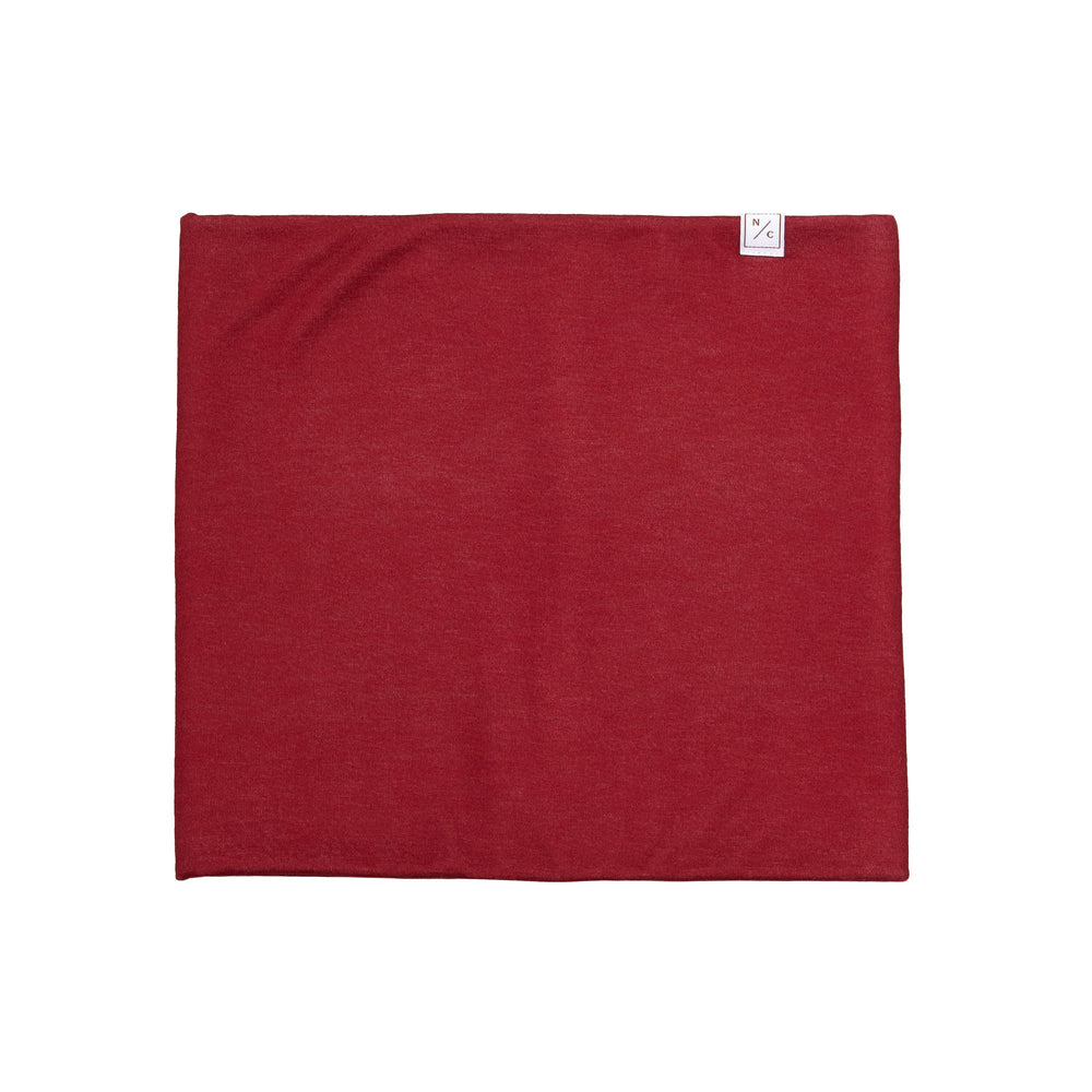 Flat lay of Heritage red fleece-lined neck warmer showing solid red fabric and small NC logo tag on white background