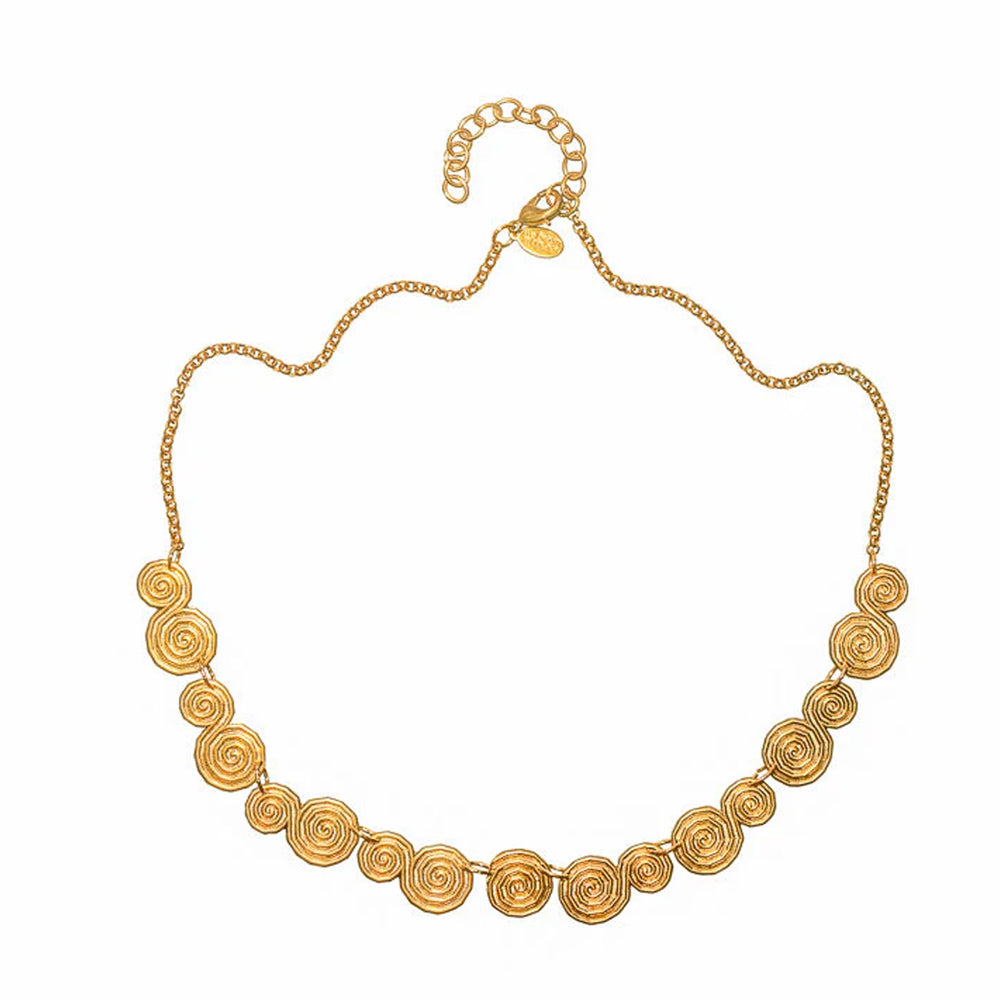 Front view of Shala Necklace showing hand-hammered spiral brass discs on a gold chain with 2-inch extender on white