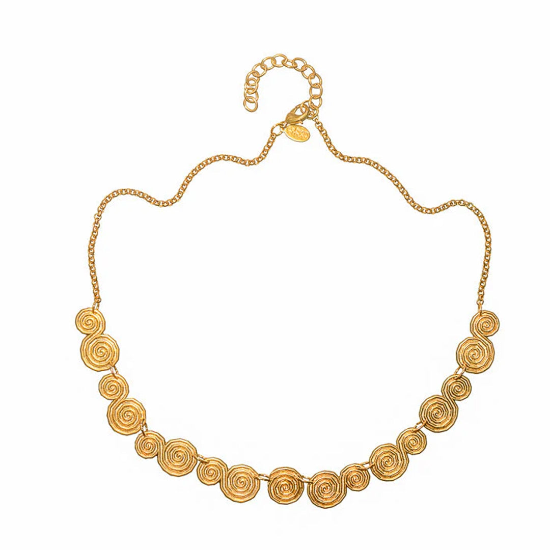 Front view of Shala Necklace showing hand-hammered spiral brass discs on a gold chain with 2-inch extender on white