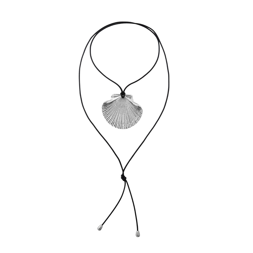 Flat lay of Venus Wrap Necklace showcasing silver-plated scallop shell pendant on adjustable black cord with silver end caps