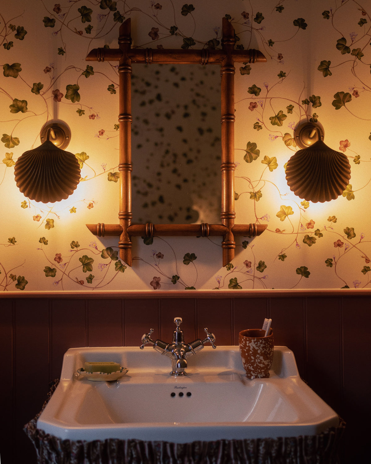 Front of Barber Mirror showcasing faux bamboo frame and small shelf above a sink with shell sconces