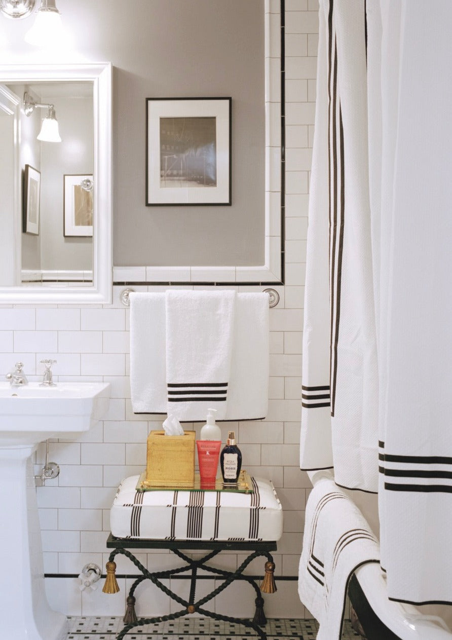 Front view of Newport shower curtain showing black triple-piping border on white fabric in a tiled bathroom setting