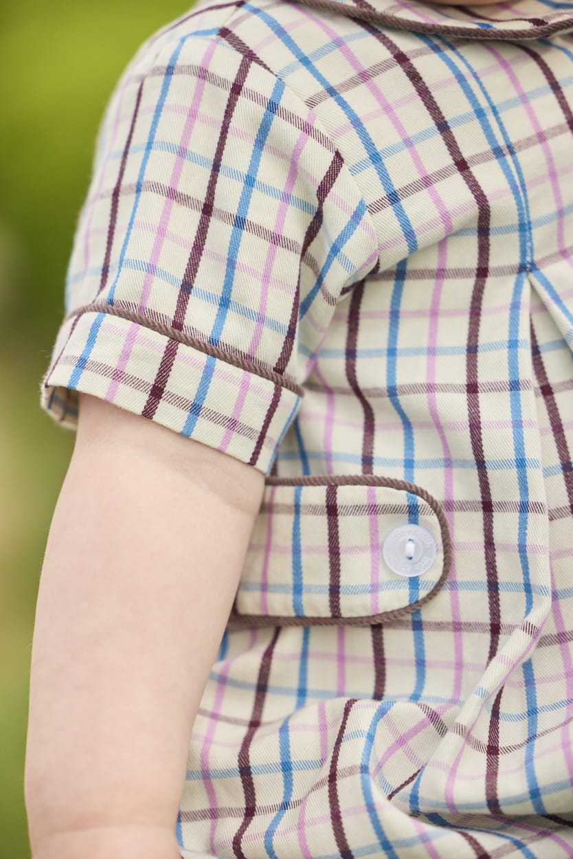 Little English traditional children's clothing.  Short sleeve peter pan bubble in brown, blue, and pink Wilmington Plaid for baby boys with button tabs and corduroy piping.