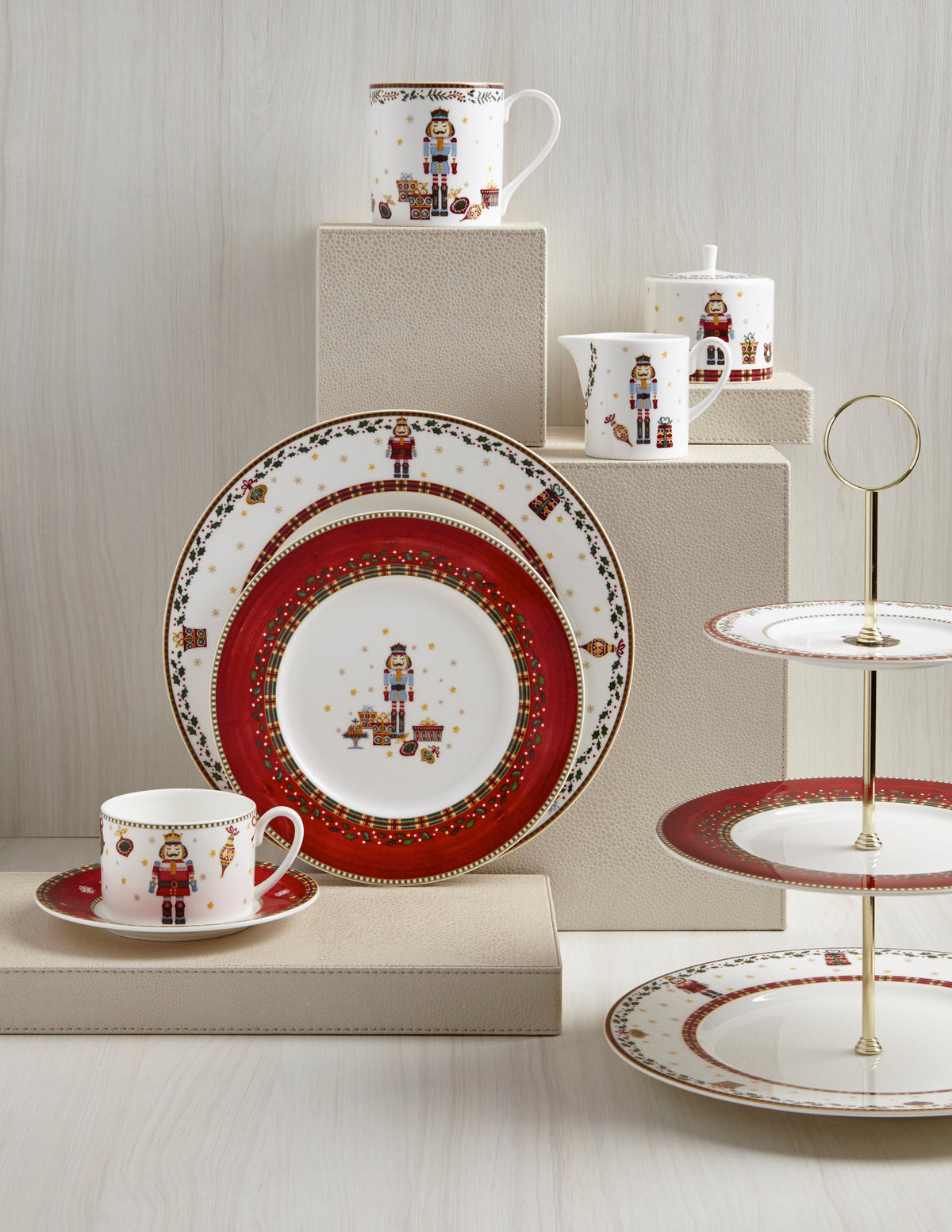Front view of Prouna Nutcracker dinnerware with plates, cup, creamer and sugar bowl, nutcracker motif and 24K gold trim