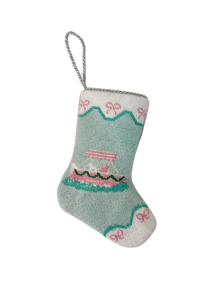 Front view of bauble stocking ornament showing needlepoint pink yacht motif, scalloped green trim, and braided hanging loop