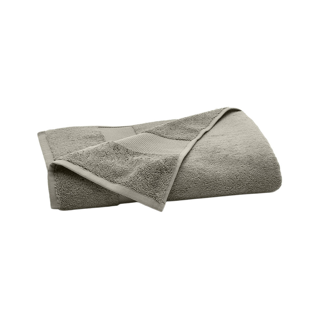 Angled view of folded plush bath towel in Juniper showcasing plush terry texture and woven hanging loop on white background