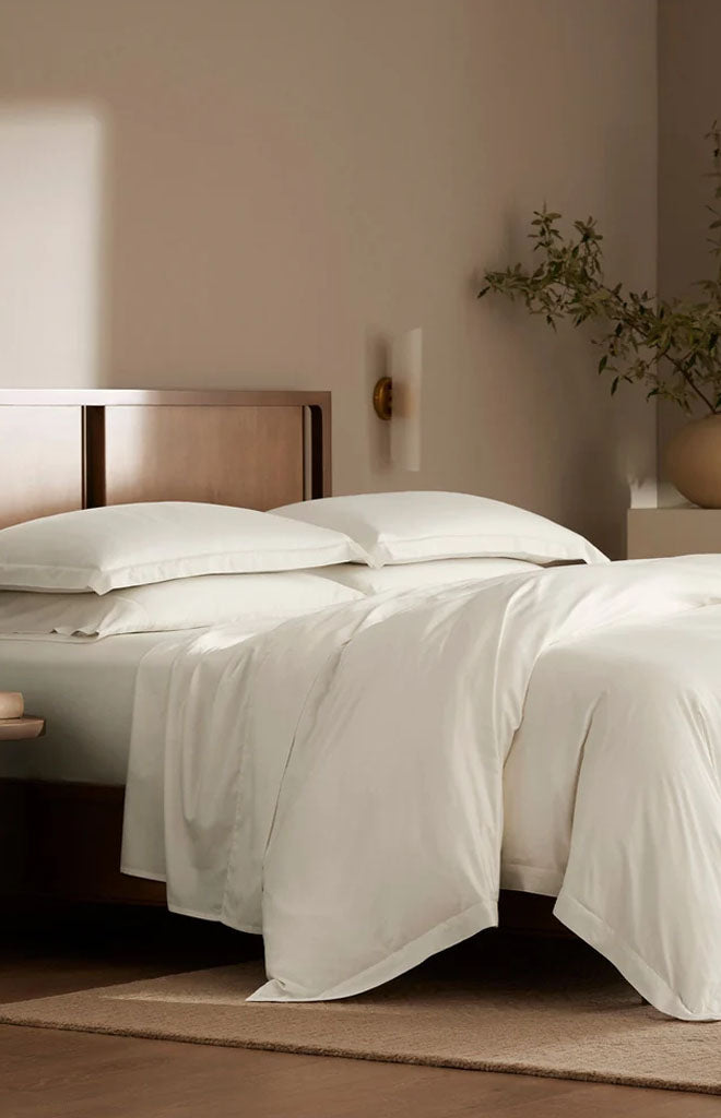 Front view of Percale Hemmed Duvet Set in Cream showcasing draped bedding on a made bed in a neutral bedroom