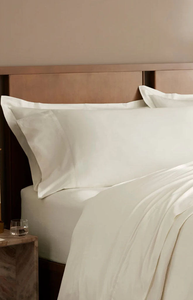 Front view of Percale Hemmed Pillowcase Set in Cream showcasing hemmed edges on a neatly made bed