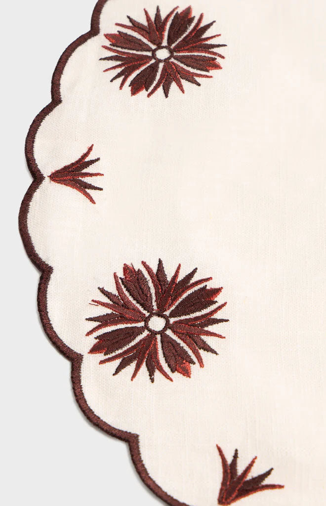 Close-up of Botanica Embroidered Placemat in White and Burgundy with floral embroidery and scalloped edge