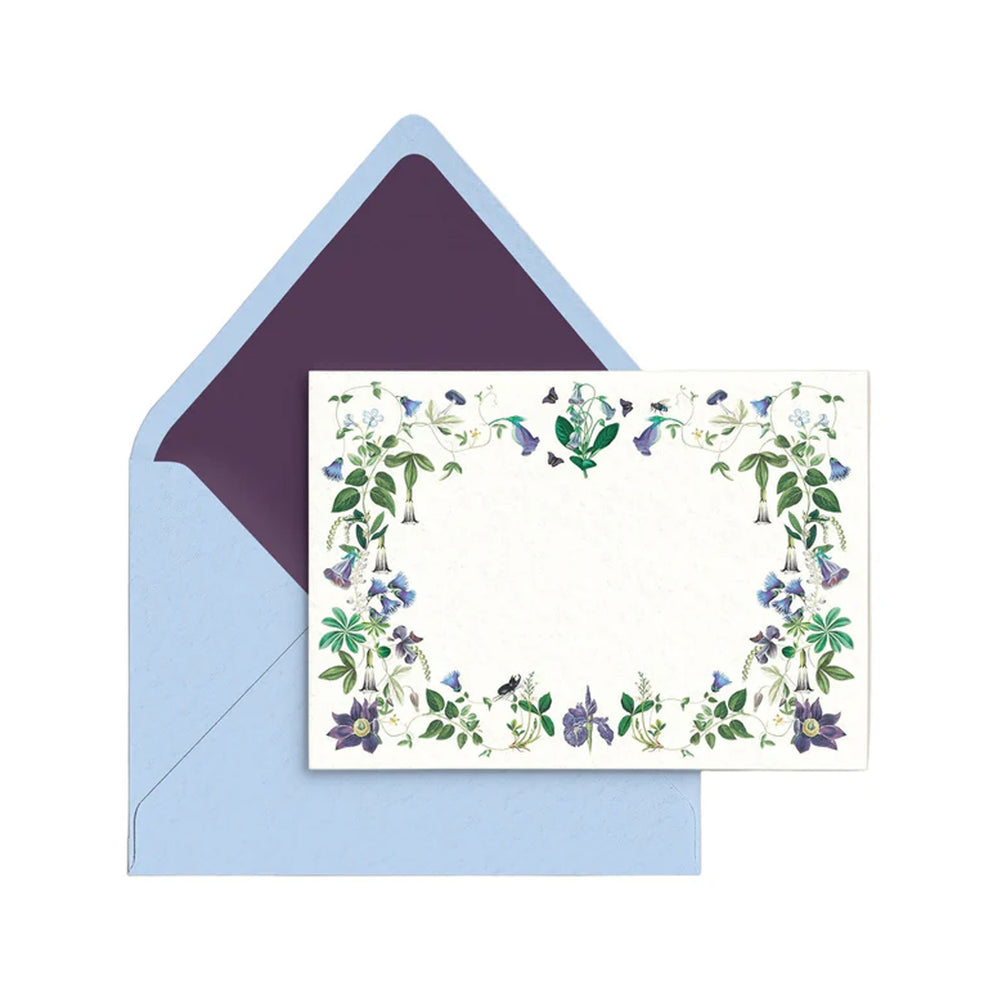Flat lay of Malvada personal stationery with floral vine border and light blue envelope with purple liner
