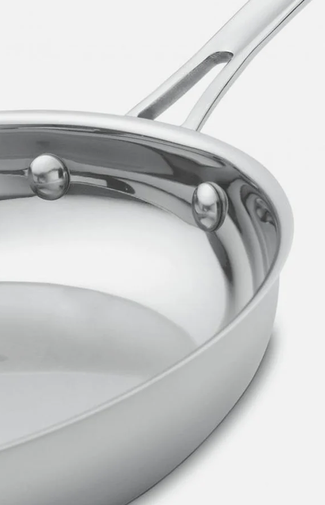 Angled close-up of Contour Collection 12 inch skillet showcasing stainless steel body and riveted handle on white background
