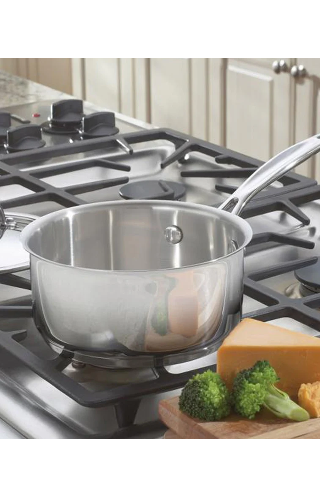 Front view of 1.5 quart Chef’s Classic stainless steel saucepan showing interior and long riveted handle on a gas stove