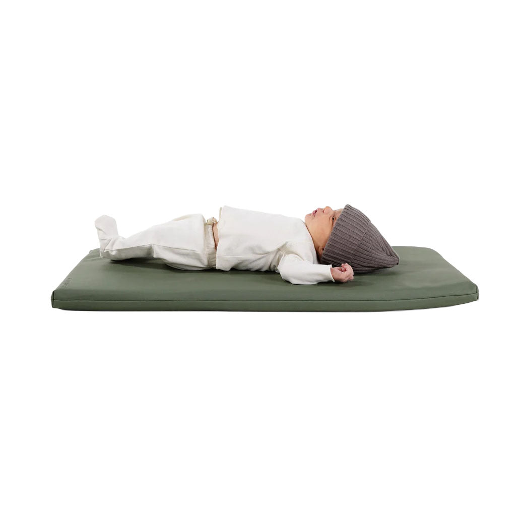 Side view of Padded Changing Mat in thyme showing cushioned memory-foam surface with a baby lying on a white background