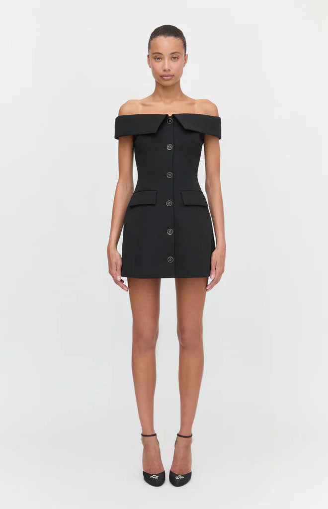 Front view of The Mattia Dress in black with off-the-shoulder neckline, button front, A-line mini skirt and front pockets
